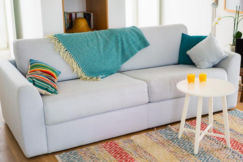 A white couch in a living room with a colorful table.