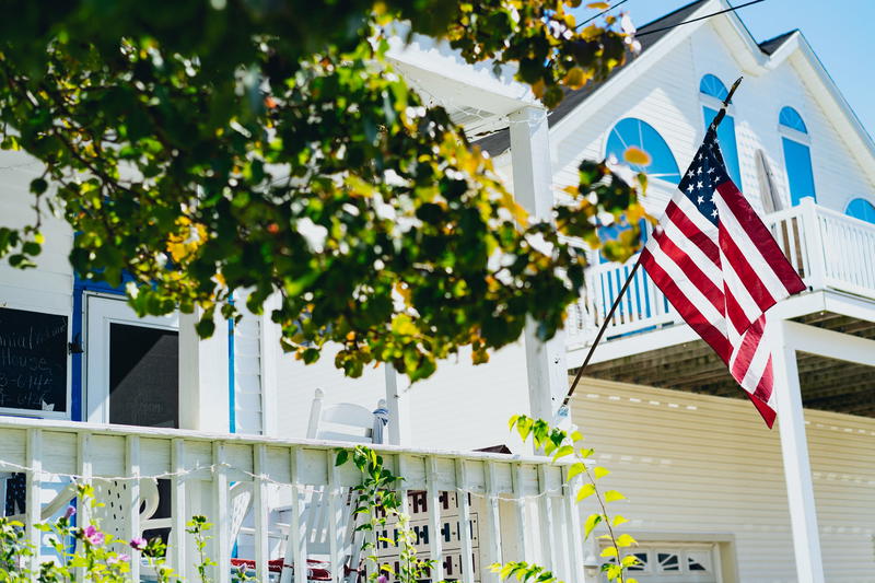A white house with an american flag on the porch.