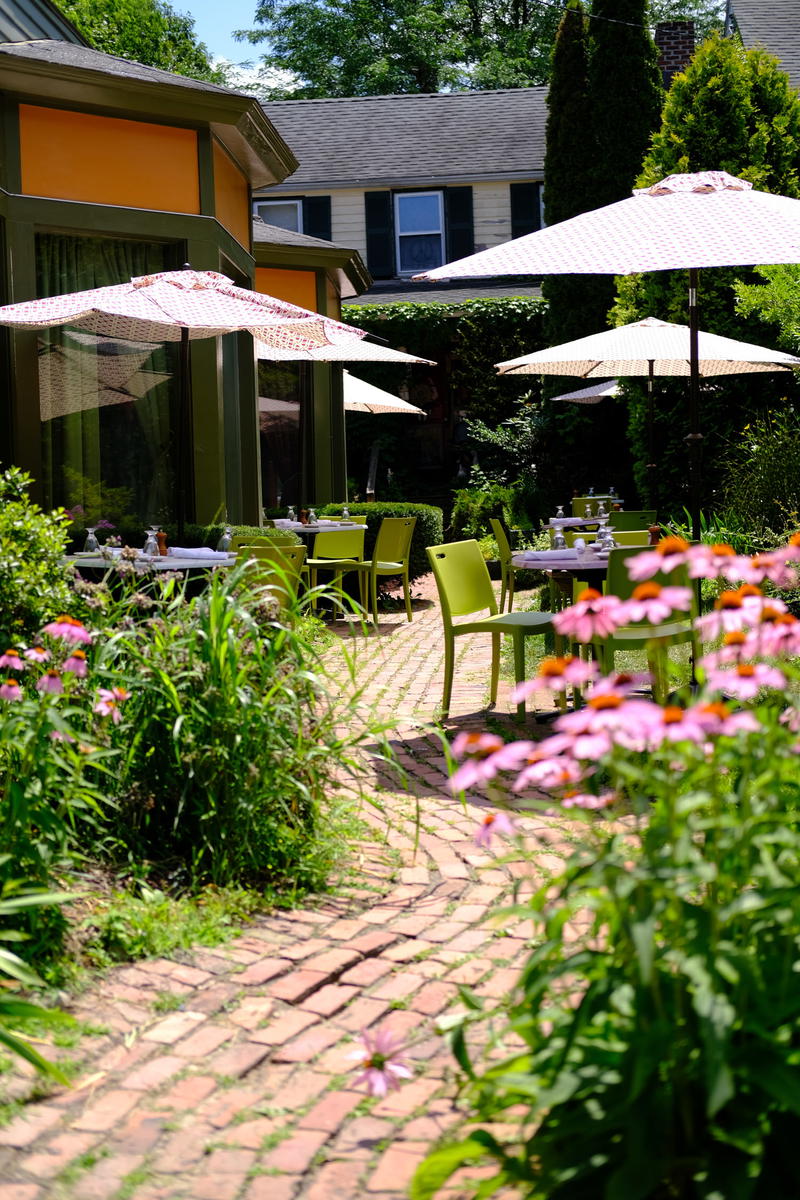 A brick patio with chairs and umbrellas.