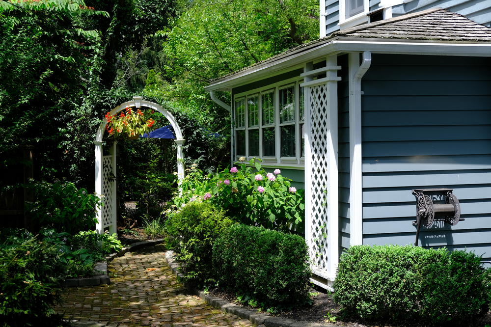 A pathway leading to a blue house with a white archway.