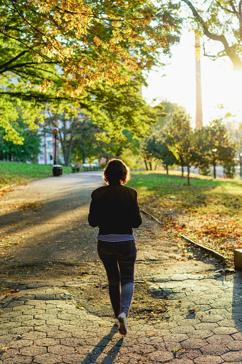 A woman walking down a path in a park.