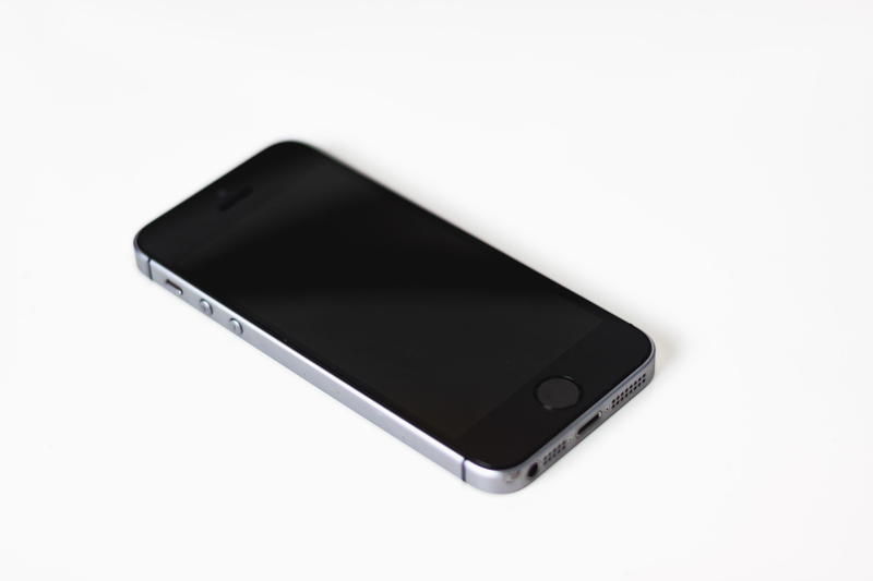 A black iphone sitting on a white surface.