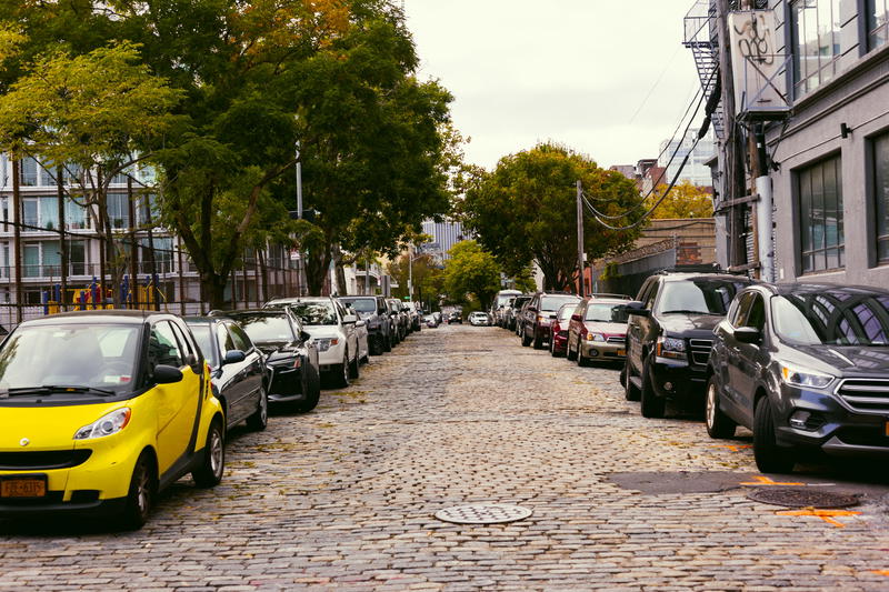 A row of cars parked on a cobblestone street.