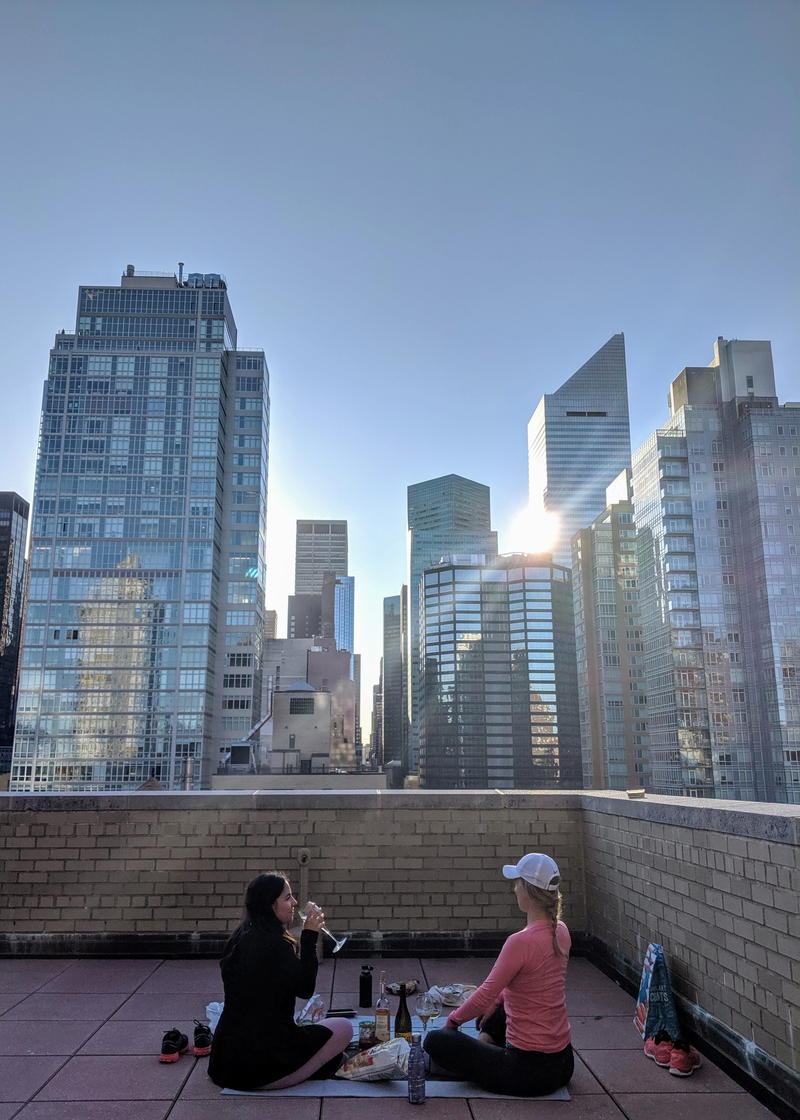 Two people sitting on a rooftop with a view of the city.
