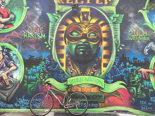 A bike parked in front of a colorful mural.