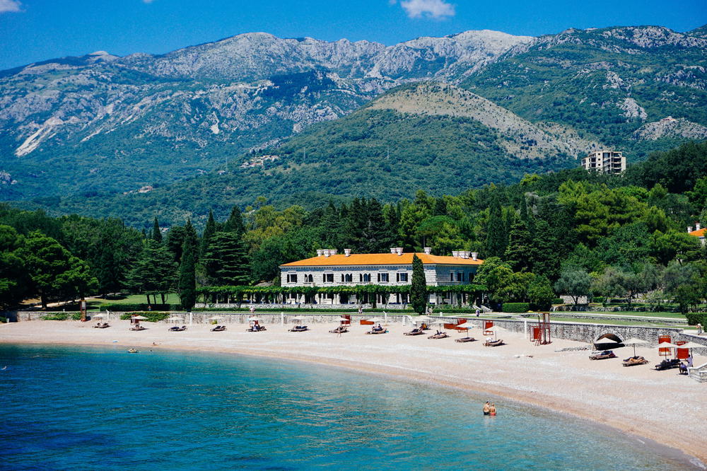 A large white house sitting on top of a lush green hillside in Budva