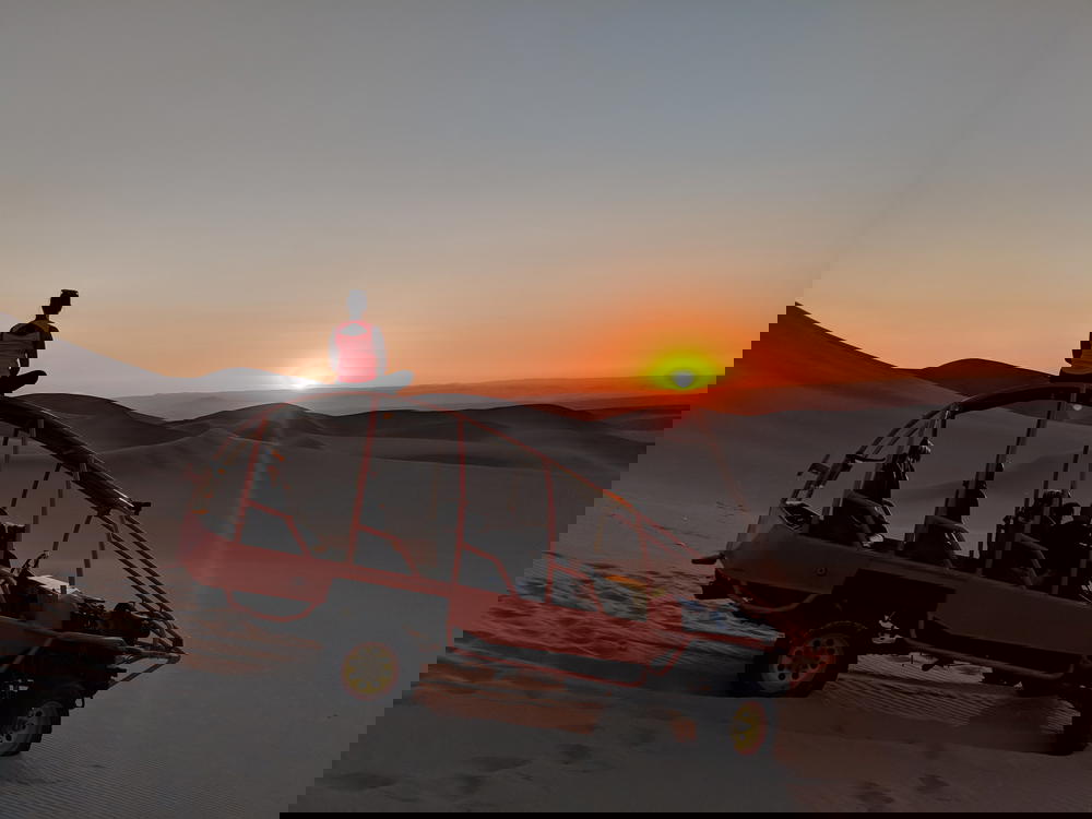 A person sitting on top of a jeep in the desert.