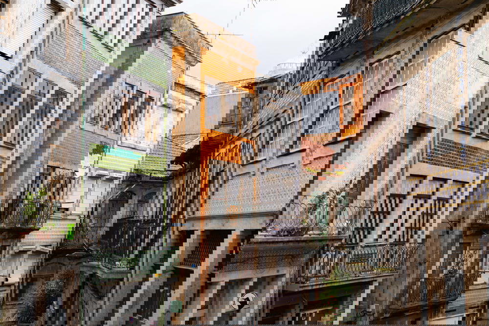 A narrow street with many buildings and balconies in Porto, Portugal.