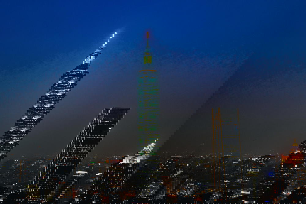 Taipei 101 lit up at night with a fading blue sky