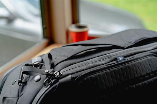 A black backpack sitting on a table next to a window.