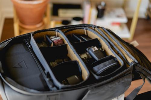 A black camera bag with a lot of compartments.
