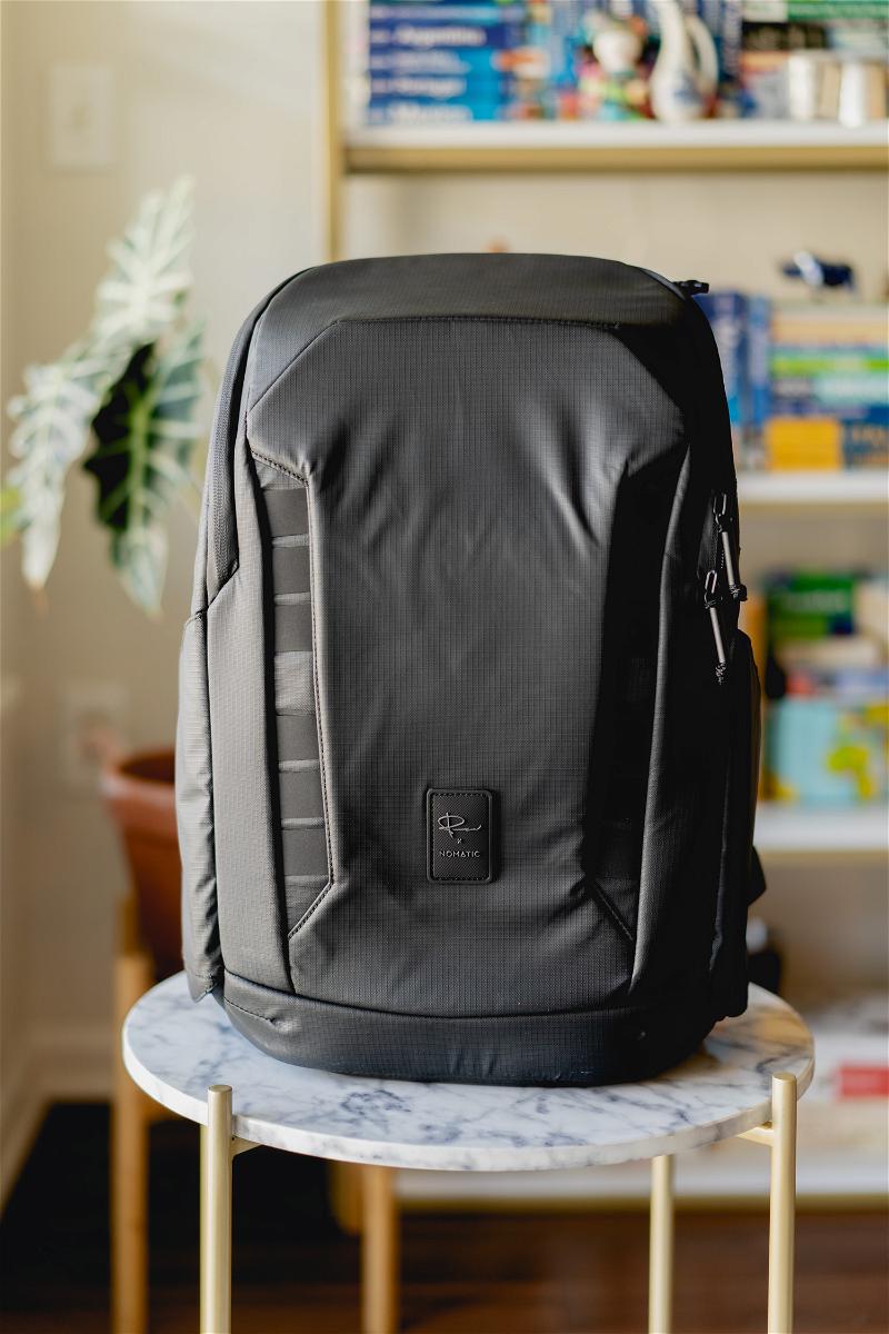 A black backpack sits on top of a marble table.