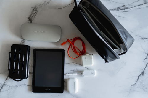 A laptop, cell phone, charger, and other items on a marble table.