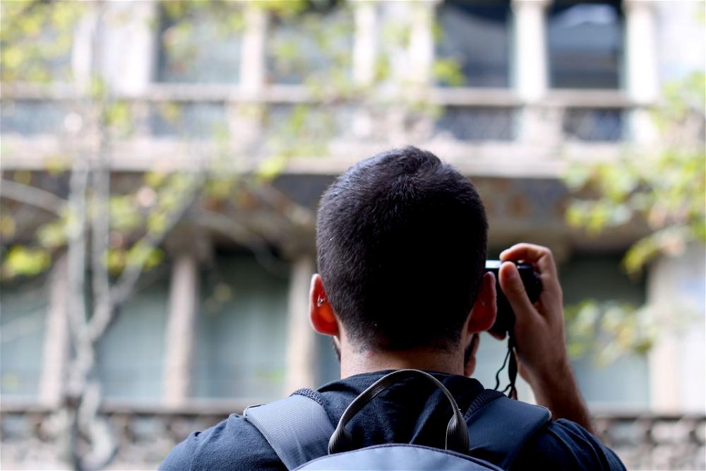 A man with a backpack taking a picture of a building.