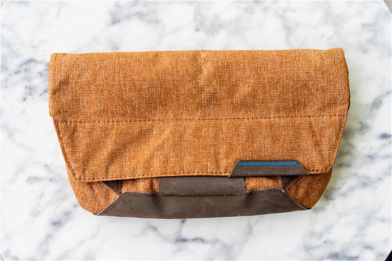 A brown messenger bag on a marble table.