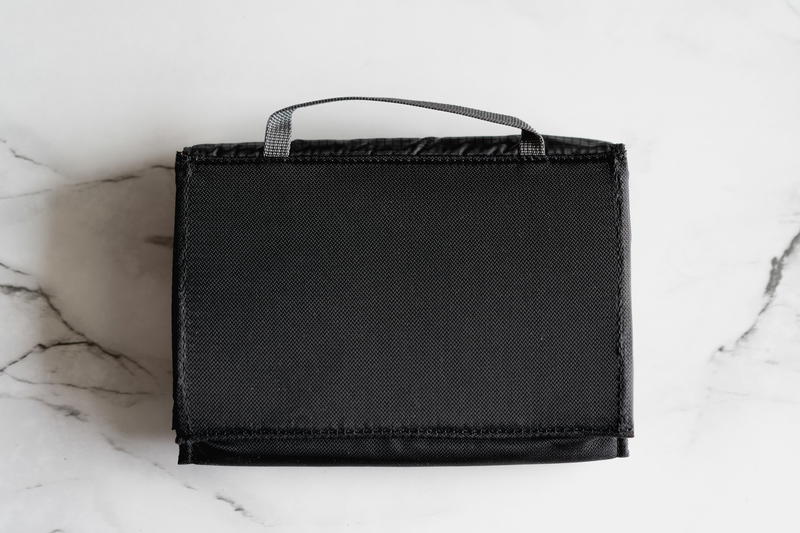 A black lunch bag sitting on a marble table.