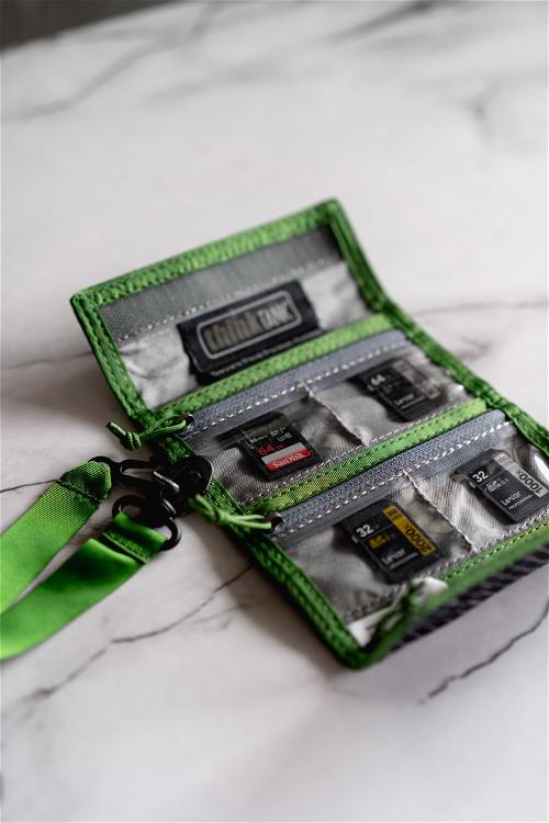 A green zippered wallet with several memory cards in it.