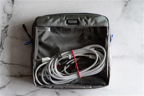 A bag filled with cables and wires on a marble countertop.