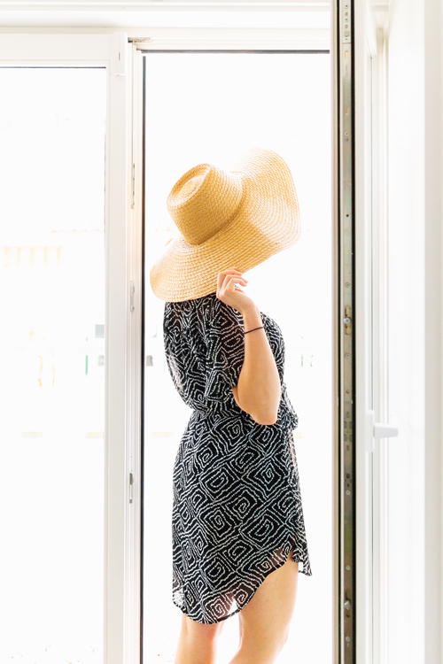 A woman wearing a hat and dress in front of a door.