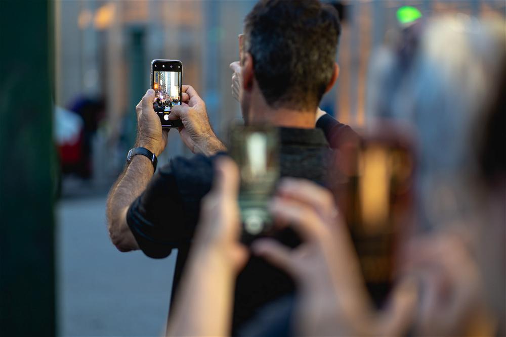 A group of people taking pictures with their cell phones.