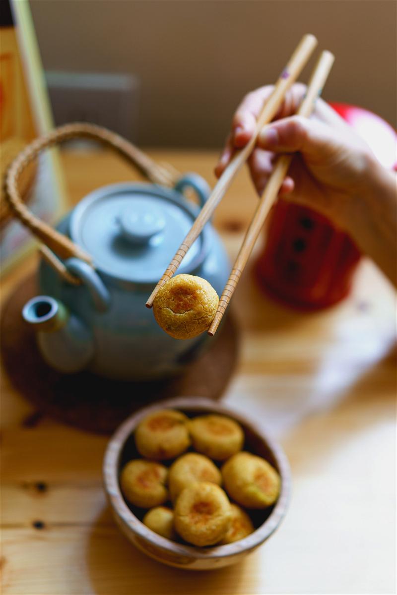 A person is holding chopsticks over a bowl of food.