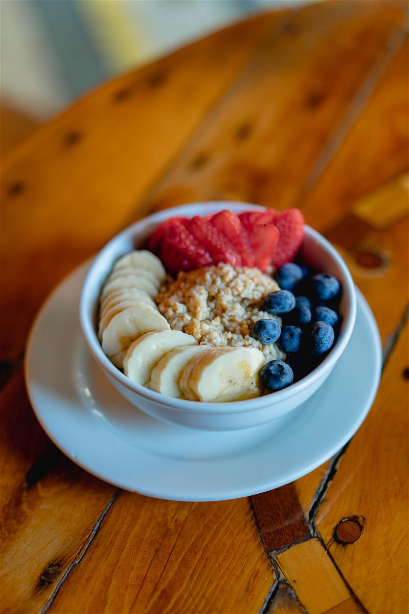A bowl of fruit and granola on a wooden table.