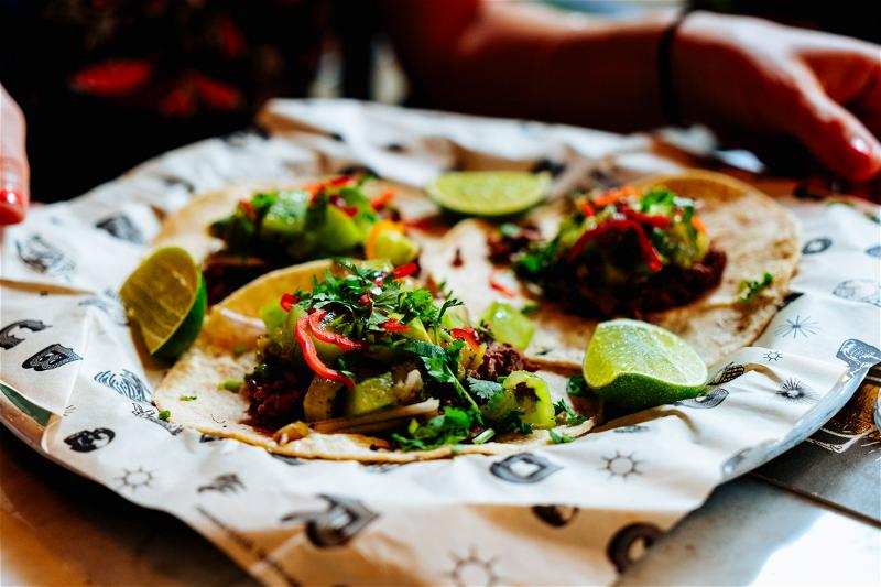 A person is holding tacos on a plate.