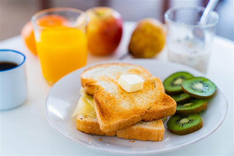 A plate of toast with kiwi slices and orange juice.