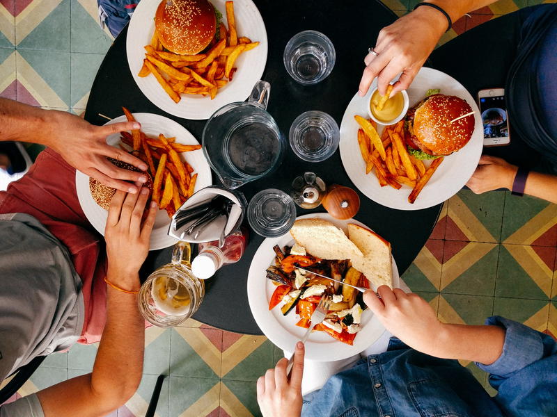 A group of people sitting around a table eating burgers and fries.