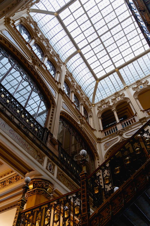 An ornate staircase in a building with a glass roof.