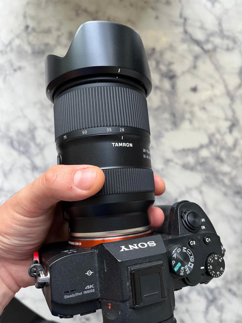 A person holding a camera with a lens attached to it.