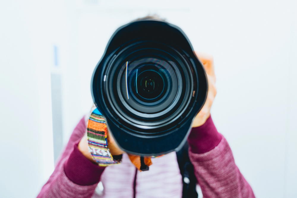 Man taking photo in a mirror with a big sony lens.