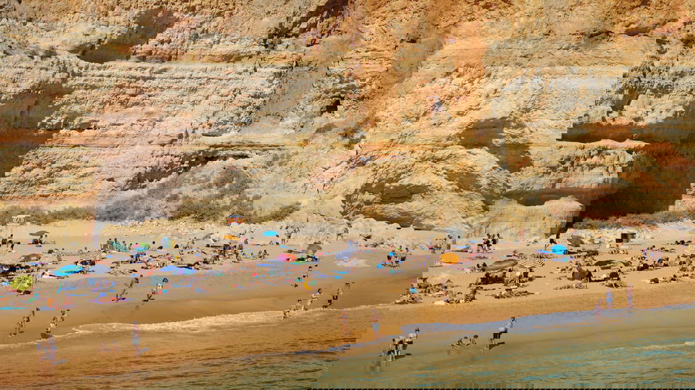Crowded beach with tall rocks off the south coast of Portugal