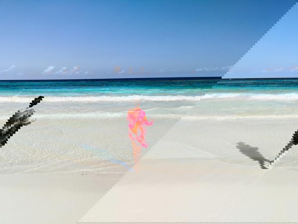 Girl with a red dress walking on a beach in Mexico