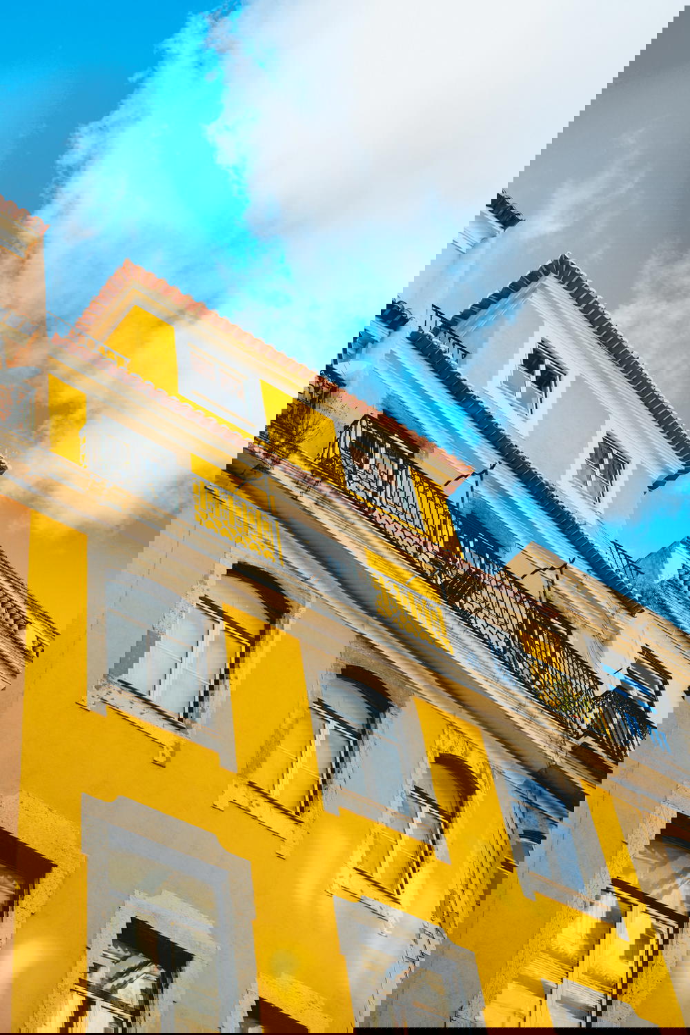 Yellow restored Lisboan architecture with red tile roof and blue sky