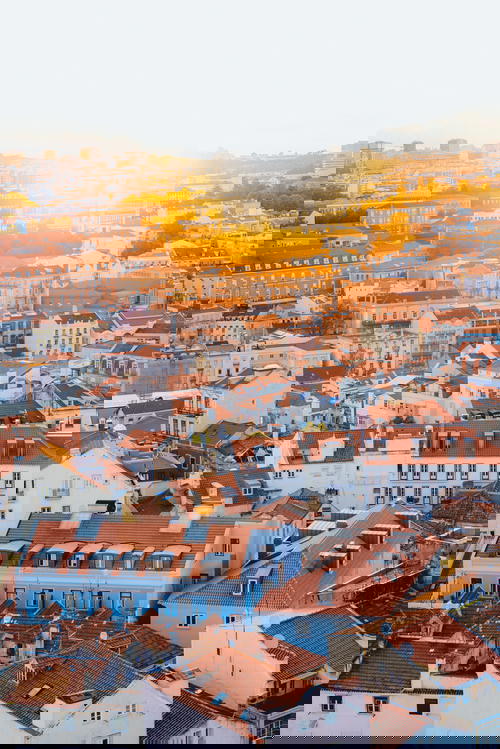 Sun going down against Lisbon tiled rooftop buildings at sunset