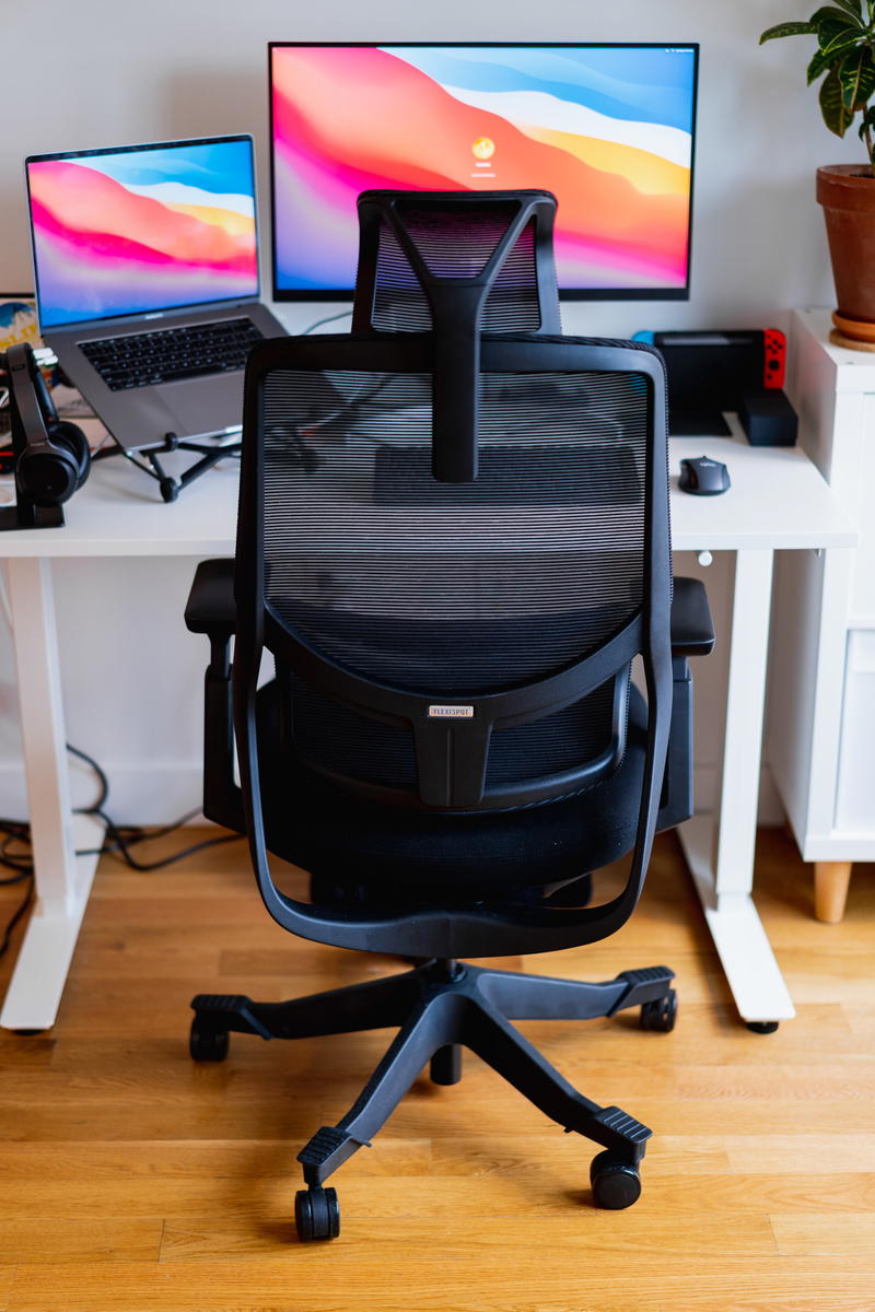 A desk with two monitors and a chair.