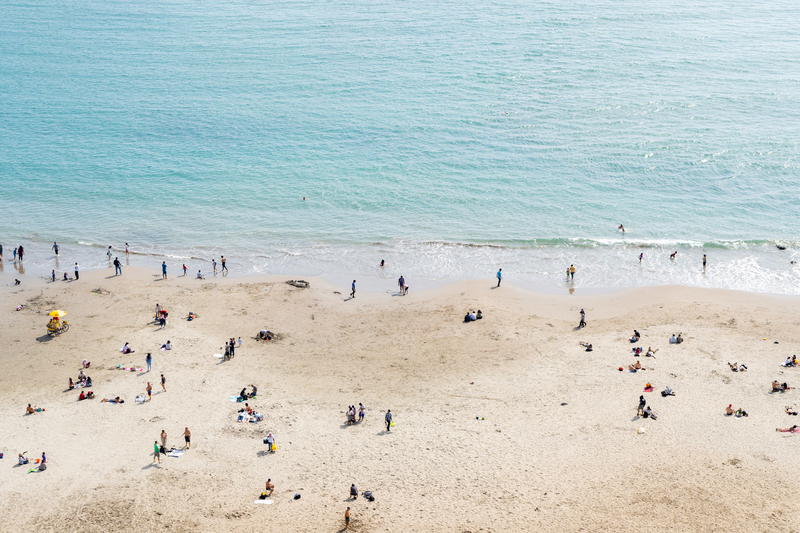People on a beach next to light blue ocean water