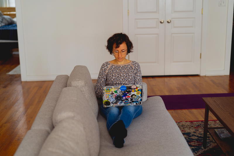 A woman sitting on a couch with a laptop.