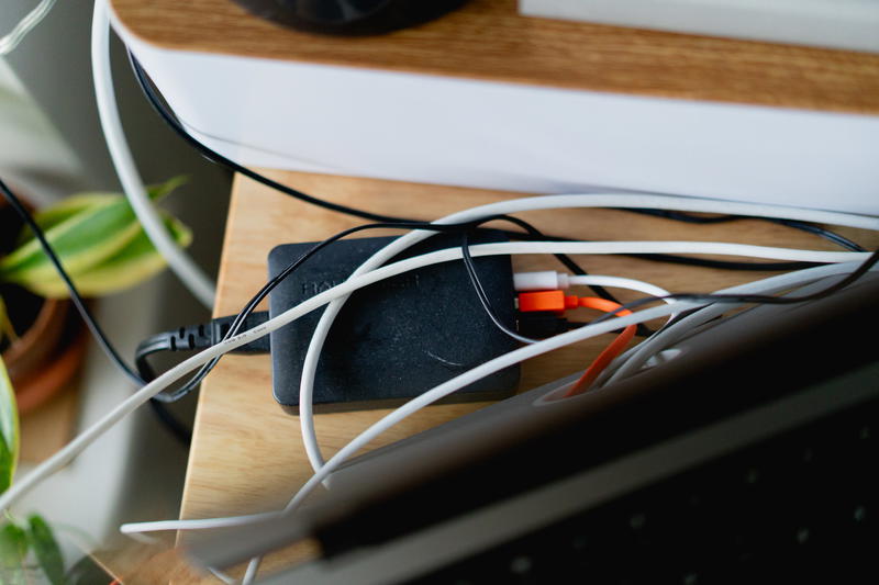 Lots of different power cables plugged into a USB powered hub on a desk.