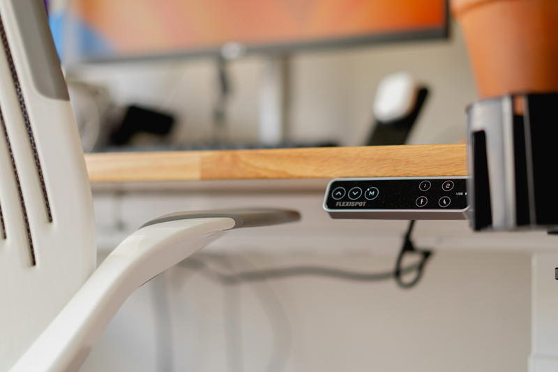 A close up of an office chair arm close to a desk.