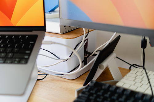 A close up of a bunch of wires coming out of a cable management box on a desk.