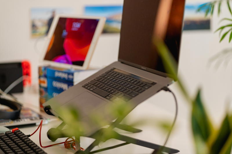 Using an iPad as an external monitor on a stack of books next to a laptop on a Roost laptop stand
