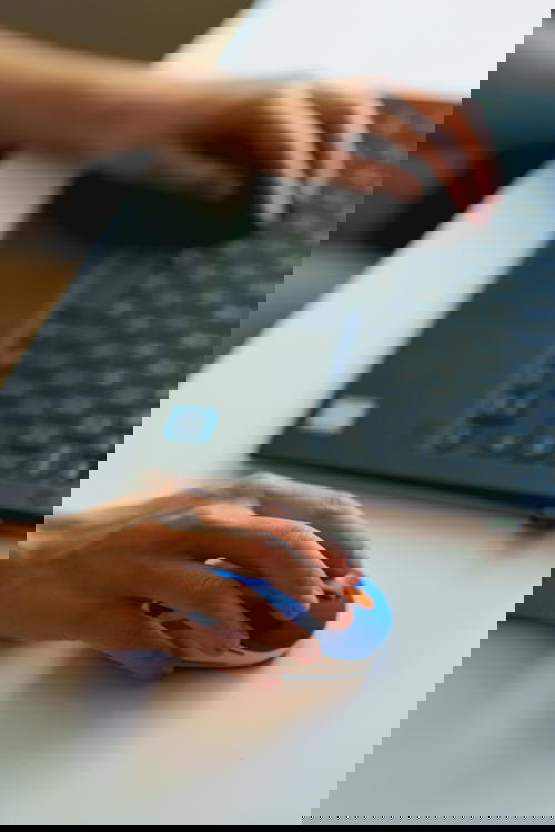 Woman using a mini logitech external mouse with a laptop in a home office