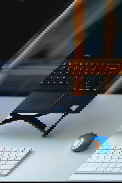 Mini logitech external mouse used with a laptop in a laptop stand and external keyboard in a home office setup