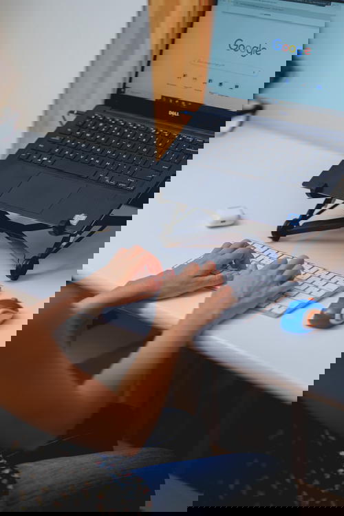 Typing and working from home at a laptop with a Roost laptop stand and external keyboard at a small desk