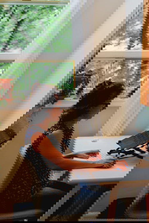 Woman working from home in a home office at a white compact desk and ergonomic ikea chair