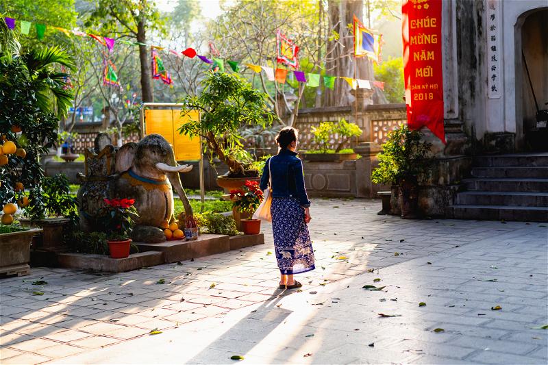 Woman wearing a blue dress and jean jacket at a Buddhist temple in Hanoi Vietnam