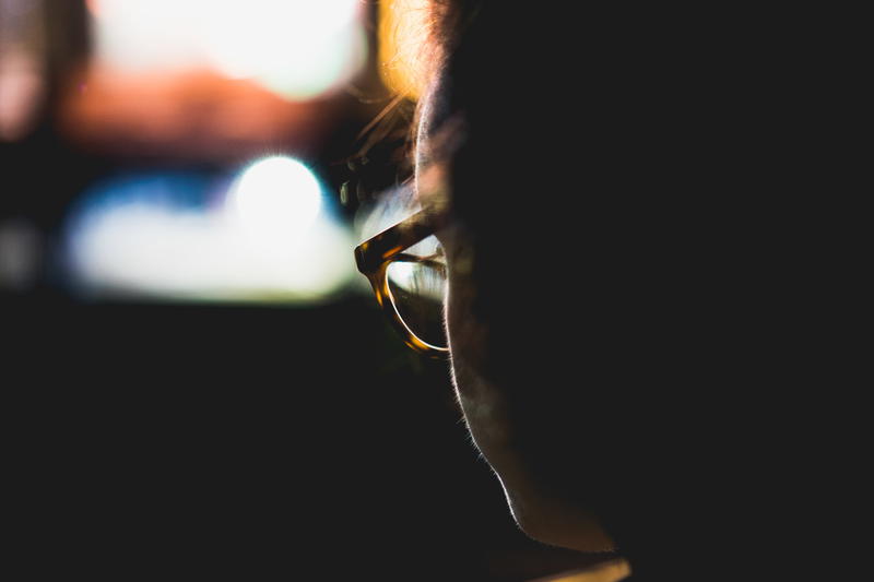 Bokeh lights behind silhouette face of a woman wearing glasses