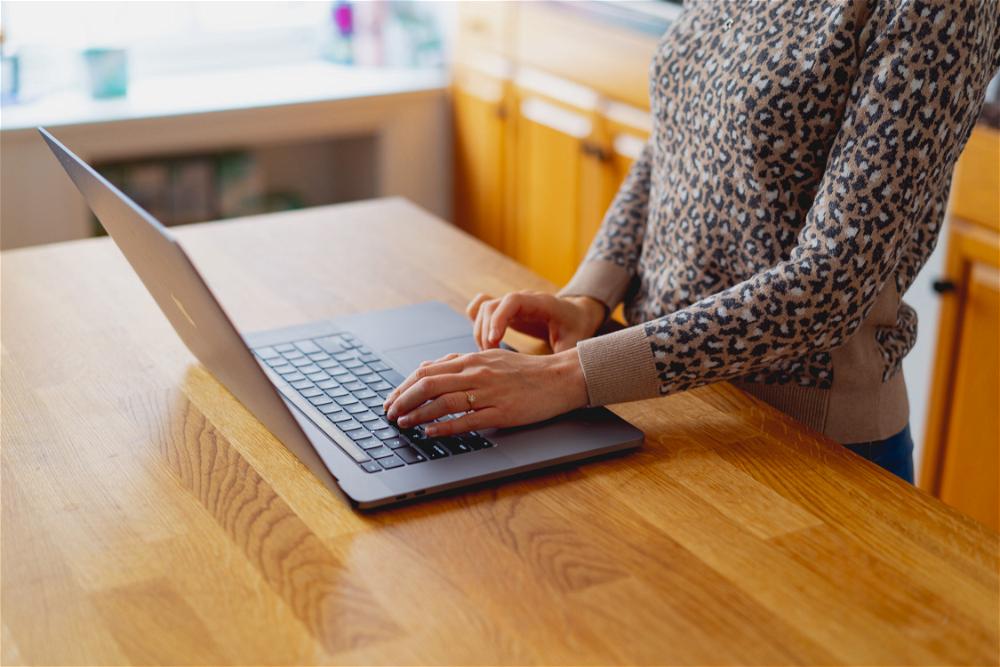 Woman's hand using a 16 inch MacBook Pro on a wooden counter